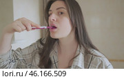 Brushing with pain: Girl perseveres, continuing to care for her health. She holds her cheek due to toothache but maintains her hygiene routine. Стоковое видео, видеограф Svetlana Golovco / Фотобанк Лори