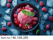 Refreshing raspberry ice cream in a black bowl, decorated with fresh mint leaves. Frozen raspberries and redcurrants are laid out around, as well as ice cubes, creating a cool effect. The background is made in a dark blue shade, which emphasizes the rich color of the berries and adds contrast to the image. Frost crystals on the surface of the dessert make it especially appetizing. Стоковое AI-изображение, AI-художник Анна Кривицкая / Фотобанк Лори