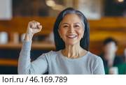 Middle aged hispanic woman with raised fist of empowerment, strength and women solidarity, International Womens Day concept. Стоковое AI-изображение, AI-художник Анастасия Золотницкая / Фотобанк Лори