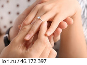 Young man putting ring on finger of his fiancee after marriage proposal, closeup. Стоковое фото, фотограф Pixel_shot / Фотобанк Лори