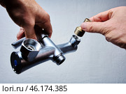 Hands attach brass eccentric reducer to plumbing fixture of . bathroom mixer tap with threaded connectors. Стоковое фото, фотограф Владимир Григорьев / Фотобанк Лори