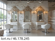 Elegant interior of a beauty salon in a classic style with elements of vintage chic. The central part is occupied by three luxurious mirrors with golden carved frames, decorated in the Baroque style. Under each mirror there are elegant white dressing tables with decorative elements.In front of the tables there are stylish white armchairs with soft upholstery and a metal base, creating a balance between classic and modern design. Lighting is represented by elegant sconces, complementing the overall atmosphere of coziness and luxury.The background is made in the form of an aged brick wall with slight abrasions, which adds vintage charm to the interior. On the right is a cosmetics storage area, and on the left are panoramic windows that let in natural light, which makes the space airy and bright. Стоковое AI-изображение, AI-художник Анна Кривицкая / Фотобанк Лори