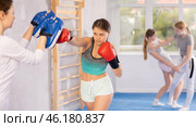 Girls works out strength and speed of boxing punch mitts with help of partner in boxing paws. Стоковое фото, фотограф Яков Филимонов / Фотобанк Лори