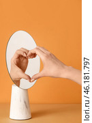 Female hand and its reflection in mirror making heart against color background. Стоковое фото, фотограф Pixel_shot / Фотобанк Лори
