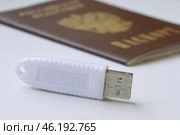 Устройство  USB eToken  (рутокен) белого цвета, устройство для хранения электронной цифровой подписи (ЭЦП) и информации для аутентификации пользователя и паспорт на белом фоне. Редакционное фото, фотограф Snezka / Фотобанк Лори