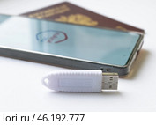 Устройство  USB eToken  (рутокен) белого цвета, устройство для хранения электронной цифровой подписи (ЭЦП) и информации для аутентификации пользователя, паспорт и телефон с приложением Госуслуги на белом фоне. Редакционное фото, фотограф Snezka / Фотобанк Лори