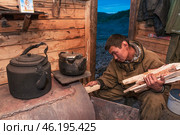 Печка, чайник, дрова, вечер в избе сибирского старателя на промысле (2010 год). Редакционное фото, фотограф Павел Просянов / Фотобанк Лори