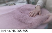 Housewife is in store, surrounded by variety of bathroom rugs. Her gaze stops on pale pink rug, which immediately attracts her attention. She picks him up, checking softness and quality of material. Стоковое видео, видеограф Скрипачев Антон / Фотобанк Лори