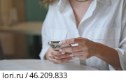Closeup footage of young female using modern smartphone while sitting at table, cropped video of woman holding mobile phone, shopping online or browsing application. Стоковое видео, видеограф Ирина Михайличенко / Фотобанк Лори