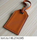 This leather hanging tag sample features a minimalist design with a sturdy loop and a slot for cards. Ideal for customizing luggage or gifts with a touch of elegance. Generative AI. Стоковое AI-изображение, AI-художник Юлия Петровская / Фотобанк Лори
