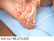 Woman's hands are attaching an electrode from a muscle stimulator to her foot, preparing for a muscle training session. Focus on fitness, wellness, and technology. Стоковое фото, фотограф Татьяна Степанищева / Фотобанк Лори