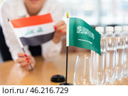 Unrecognizable girl sets midget flags of Saudi Arabia and Iraq before international negotiations. Стоковое фото, фотограф Яков Филимонов / Фотобанк Лори