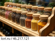 An organized set of glass jars with various spices and seasonings, neatly arranged on a wooden shelf. Each jar is closed with a cork lid, which adds aesthetics and coziness. Inside are spices of different colors and textures - from black pepper and coriander to turmeric and dried herbs. The background is slightly blurred, which helps to focus attention on the foreground, where the details of the jars and their contents are clearly visible. The atmosphere of the photo conveys the warmth of the kitchen, the care taken in storing ingredients, and the aesthetics of order. Стоковое AI-изображение, AI-художник Анна Кривицкая / Фотобанк Лори