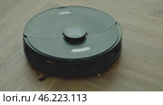 round robot vacuum moves methodically across the bathroom floor, its sensors scanning for dust and hair. Стоковое видео, видеограф Feruza Tashmetova / Фотобанк Лори