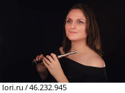 Woman holding piccolo flute against black background. Studio portrait of female musician. Classical music and performance concept. Стоковое фото, фотограф Андрей Журавлев / Фотобанк Лори