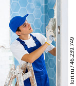 Young builder laying tiles on walls during indoor overhaul. Стоковое фото, фотограф Яков Филимонов / Фотобанк Лори