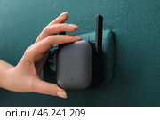 Woman plugging black WiFi repeater in electric socket on green wall. Стоковое фото, фотограф Pixel_shot / Фотобанк Лори