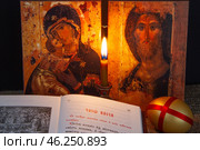 Православный натюрморт. Складень с иконами Спаса и Богородицы, свеча золотое яйцо и молитвослов, открытый на странице с Часами Пасхи. Стоковое фото, фотограф Александр Рыбалка / Фотобанк Лори