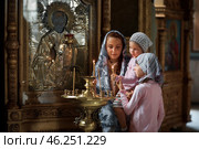 Young mother and her little blond Caucasian daughter with candles in Orthodox Russian Church. Стоковое фото, фотограф Арзюков Вадим Николаевич / Фотобанк Лори