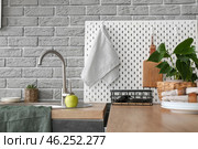Modern counter and pegboard with kitchen utensils near grey brick wall. Стоковое фото, фотограф Pixel_shot / Фотобанк Лори