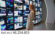 Businesswoman looking at multiple tv screens showing different multimedia content. Стоковое видео, видеограф Данил Руденко / Фотобанк Лори