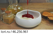 Stream of tomato paste pours into bowl of sour cream. Seasonings are arranged on the table, adding flavor to sauce. Close up. High angle. Стоковое видео, видеограф Strunov David / Фотобанк Лори