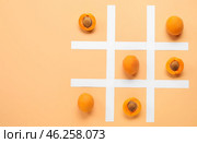 Tic tac toe game with ripe apricots and paper grid on color background. Стоковое фото, фотограф Pixel_shot / Фотобанк Лори