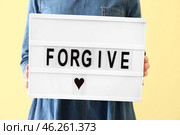 Woman holding board with word FORGIVE on color background, closeup. Стоковое фото, фотограф Pixel_shot / Фотобанк Лори