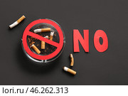 Paper word NO, stop sign, ashtray and cigarette butts on black background, closeup. Stop smoking concept. Стоковое фото, фотограф Pixel_shot / Фотобанк Лори