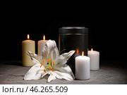 Mortuary urn, burning candles and flower on table against dark background. Стоковое фото, фотограф Pixel_shot / Фотобанк Лори