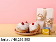 Plate with tasty donuts, dreidel and gift for Hannukah celebration on color background. Стоковое фото, фотограф Pixel_shot / Фотобанк Лори