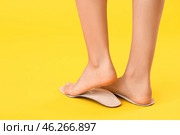 Female feet and orthopedic insoles on yellow background. Стоковое фото, фотограф Pixel_shot / Фотобанк Лори