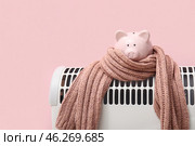 Electric convector heater, piggy bank and scarf on pink background. Heating season. Стоковое фото, фотограф Pixel_shot / Фотобанк Лори