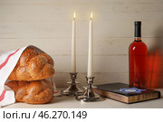 Traditional challah bread with glowing candles, Torah and bottle of wine on white wooden background. Shabbat Shalom. Стоковое фото, фотограф Pixel_shot / Фотобанк Лори