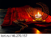 Arabic candle holder with glowing candle, carpet and tasbih on dark background. Стоковое фото, фотограф Pixel_shot / Фотобанк Лори