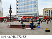 Уличный музыкант играет музыку возле "Часов Мира". Площадь Тукая. Город Казань. Республика Татарстан. Россия (2024 год). Редакционное фото, фотограф Александр Тараканов / Фотобанк Лори