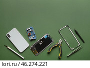 Disassembled mobile phone with technician tools on color background. Стоковое фото, фотограф Pixel_shot / Фотобанк Лори
