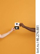 Hands of Caucasian woman and African-American man holding paper sheets with drawn heart on color background. Racism concept. Стоковое фото, фотограф Pixel_shot / Фотобанк Лори