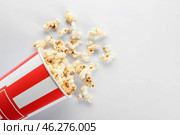 Overturned paper cup of tasty popcorn on white background. Стоковое фото, фотограф Pixel_shot / Фотобанк Лори