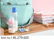 Bottles of milk for baby with pacifiers and clothes on table. Стоковое фото, фотограф Pixel_shot / Фотобанк Лори