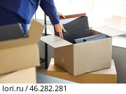 Businesswoman packing belongings into cardboard box in office on moving day. Стоковое фото, фотограф Pixel_shot / Фотобанк Лори