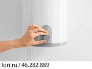 Woman adjusting boiler on light wall, closeup. Стоковое фото, фотограф Pixel_shot / Фотобанк Лори