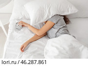 Morning of young woman sleeping with alarm clock in bed. Стоковое фото, фотограф Pixel_shot / Фотобанк Лори