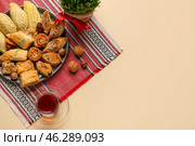 Plate with treats, grass and glass of tea on beige background. Novruz Bayram celebration. Стоковое фото, фотограф Pixel_shot / Фотобанк Лори