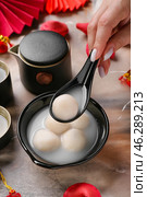 Woman with spoon and bowl of tangyuan on grunge background, closeup. Dongzhi Festival. Стоковое фото, фотограф Pixel_shot / Фотобанк Лори