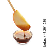 Dipping of apple wedge into glass bowl with sauce on white background. Стоковое фото, фотограф Pixel_shot / Фотобанк Лори