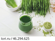 Glass with fresh wheatgrass juice and powder on light background. Стоковое фото, фотограф Pixel_shot / Фотобанк Лори