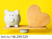 Piggy bank and wooden heart on teeterboard against color background. Concept of balance. Стоковое фото, фотограф Pixel_shot / Фотобанк Лори