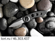 Folding pocket knife with rubberized handle on rocks background. Стоковое фото, фотограф Pixel_shot / Фотобанк Лори