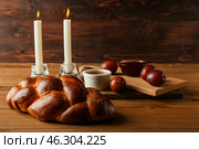 Traditional challah bread with glowing candles on wooden background. Shabbat Shalom. Стоковое фото, фотограф Pixel_shot / Фотобанк Лори